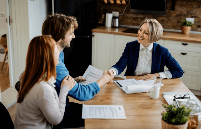 happy-insurance-agent-shaking-hands-with-young-couple-after-successful-meeting