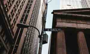 Wall Street street sign with tall buildings and historic architecture in NYC.